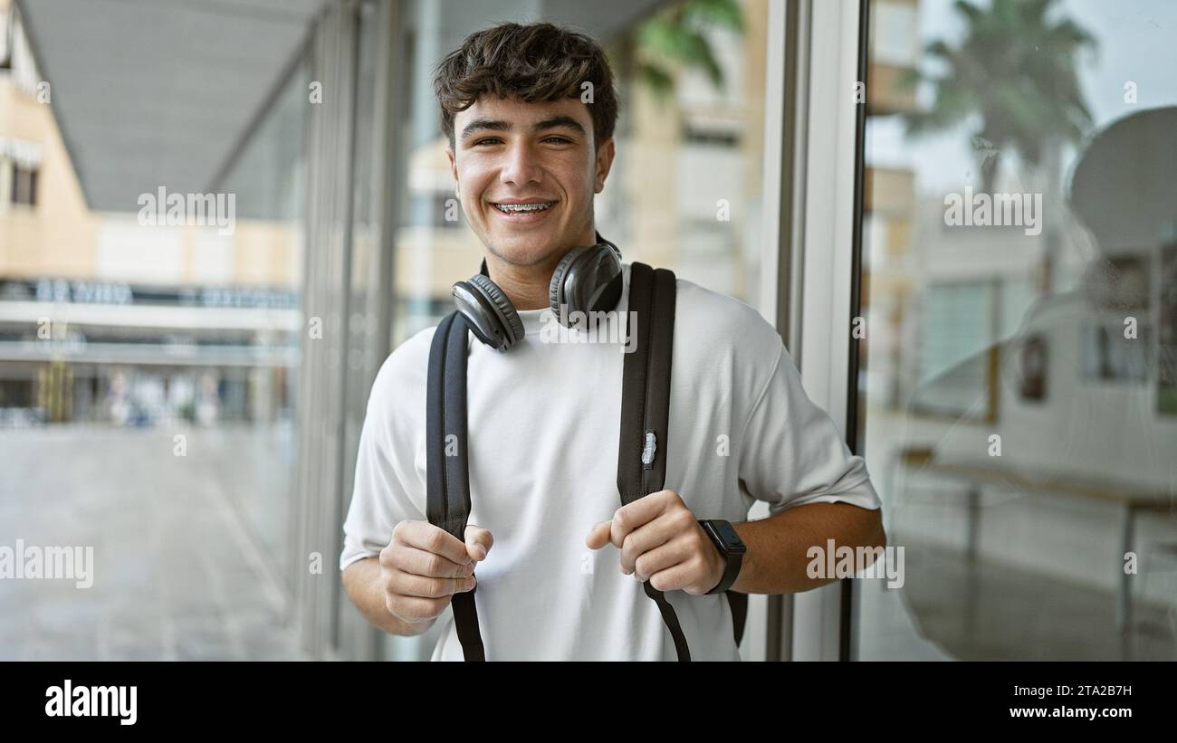Cheerful young hispanic male student standing outdoors enjoying campus ...