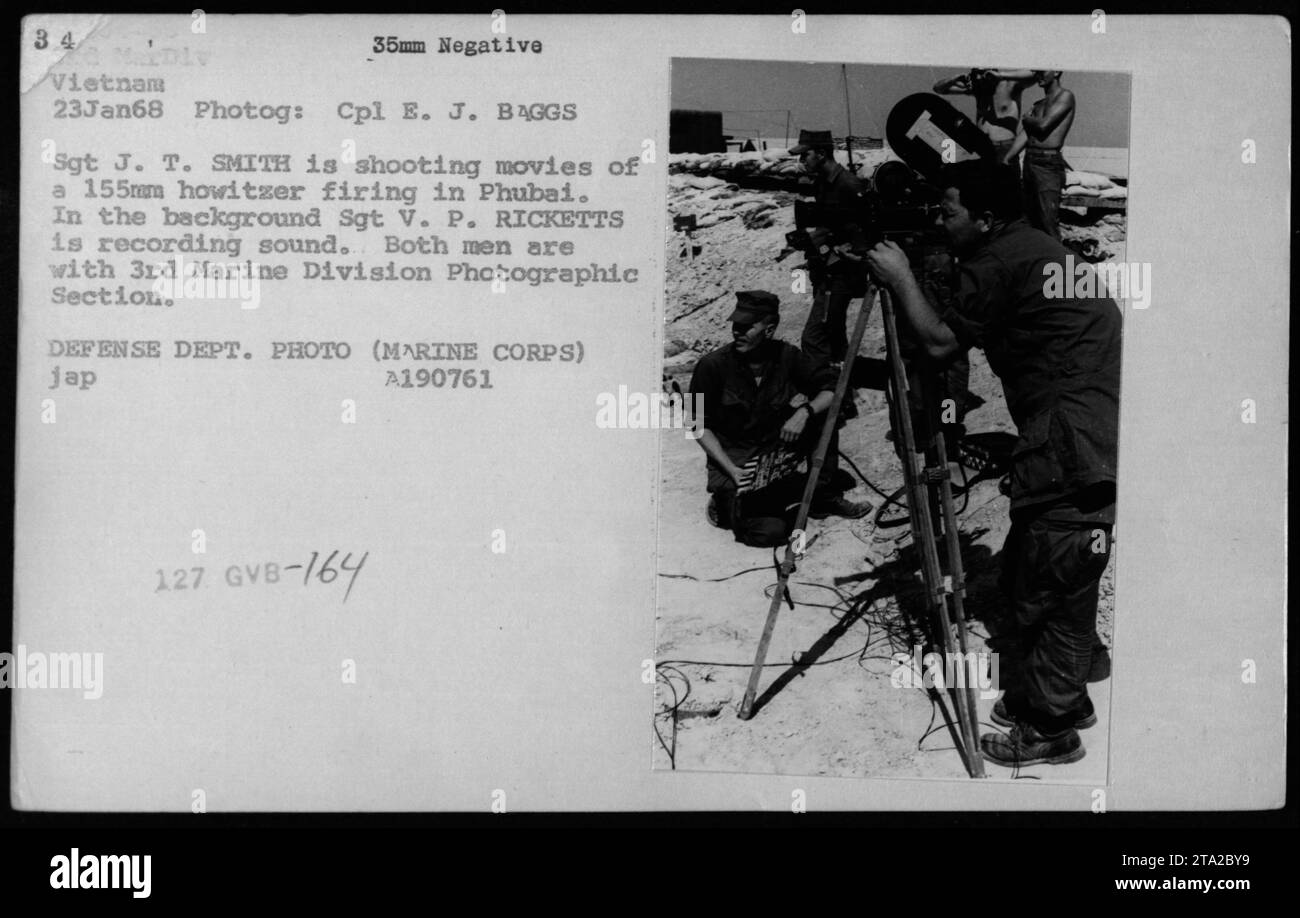 Sgt J. T. Smith films a 155mm howitzer being fired in Phubai, Vietnam on January 23, 1968. Sgt V. P. Ricketts records sound in the background. Both men belong to the 3rd Marine Division Photographic Section, captured in this image taken by Cpl E. J. Baggs. Stock Photo