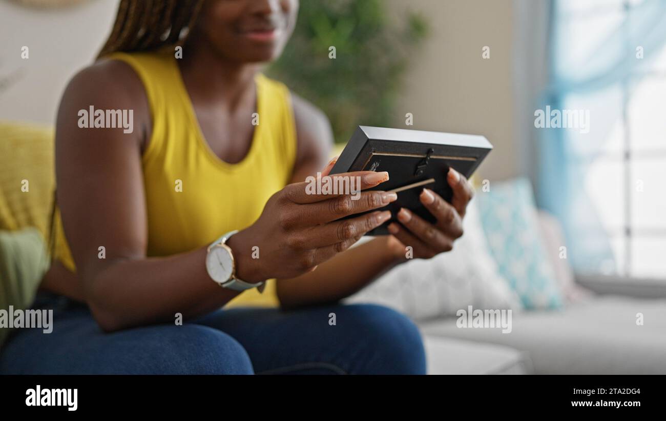 African american woman sitting on sofa looking photo at home Stock ...