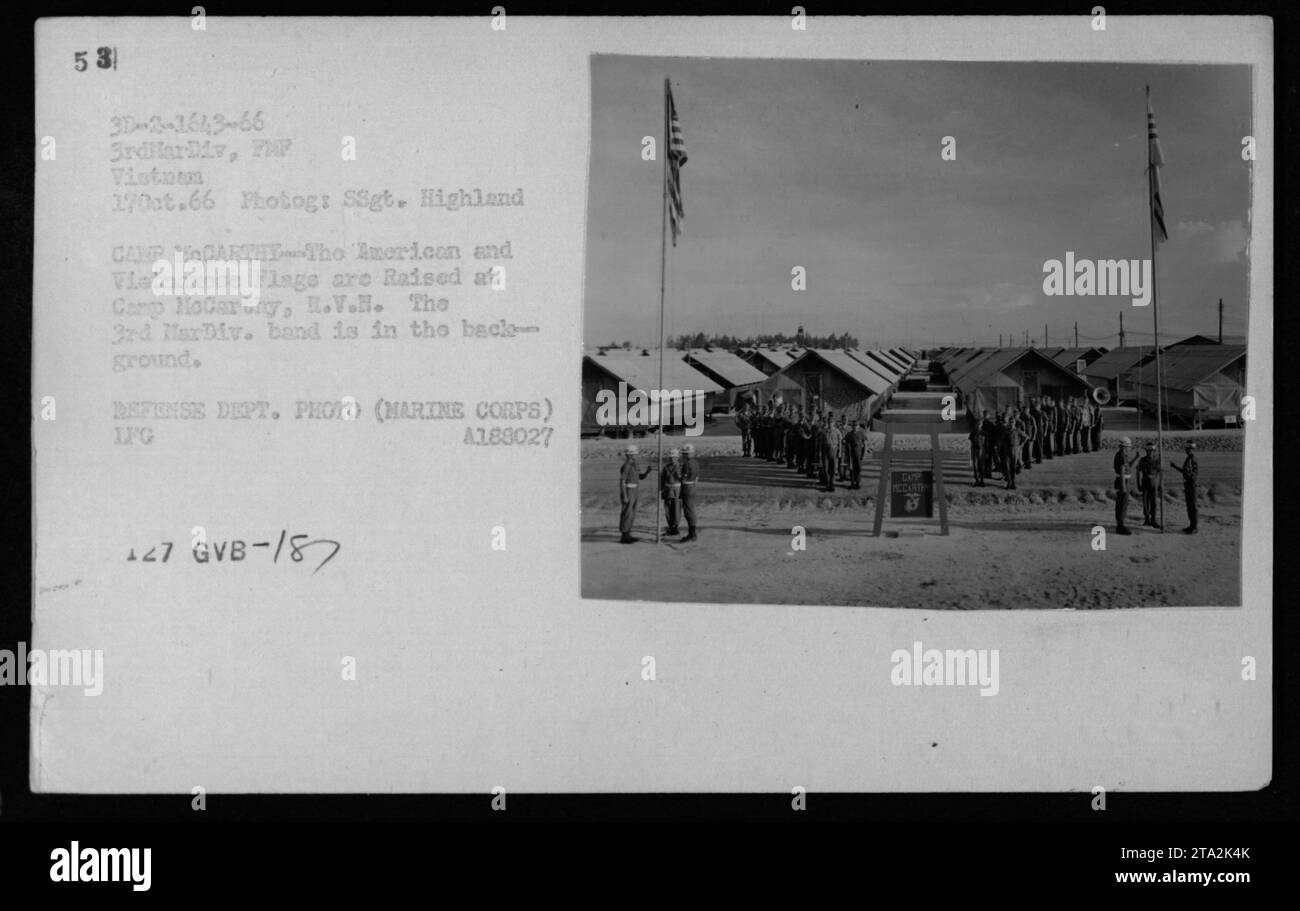 American and Vietnamese flags are raised at Camp McCarthy, R.V.H, during a flag ceremony on October 17, 1966. The image shows the 3rd MarDiv. band in the background. This photograph is from a collection of American military activities during the Vietnam War. Stock Photo