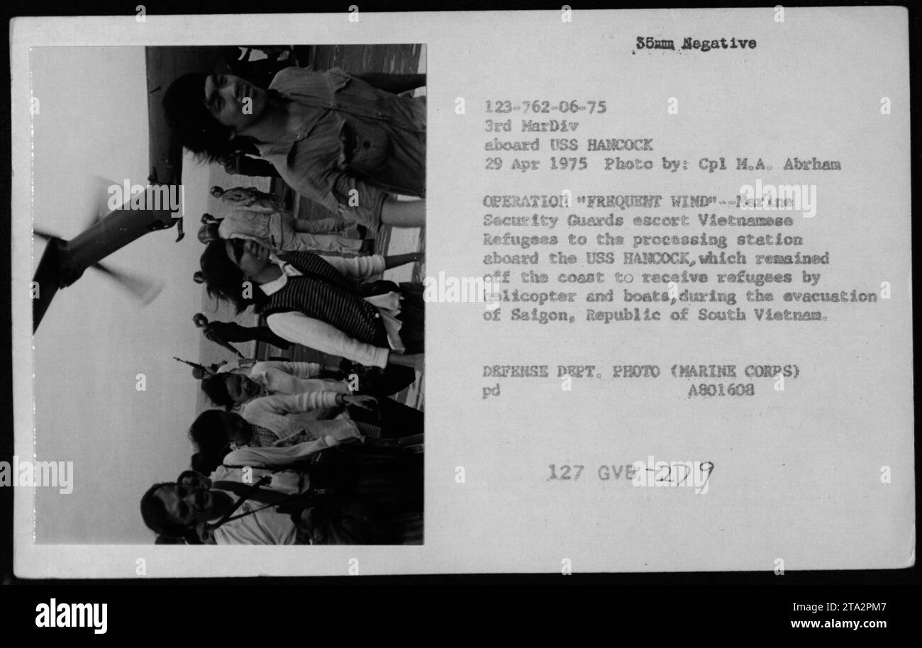 Marine Security Guards are seen escorting Vietnamese refugees to a processing station on the USS HANCOCK during Operation Frequent Wind. The USS HANCOCK remained off the coast to receive refugees by helicopter and boats during the evacuation of Saigon, Republic of South Vietnam on April 29, 1975. This photo was taken by Cpl M.A. Abrham. Stock Photo