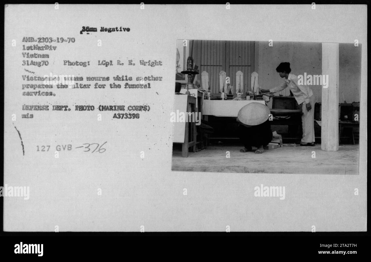 Vietnamese women mourn during funeral preparations in August 1970. The image, taken by LCpl R. E. Wright, depicts one woman in mourning while another prepares the altar. This photograph was part of a series capturing civil life in Vietnam during the war. Source: DEFENSE DEPT. PHOTO (MARINE CORPS) A373398. Stock Photo