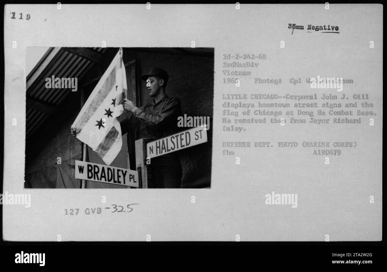 'Cpl. John J. Gill proudly showcases street signs and the flag of Chicago at Dong Ha Combat Base. These items were a gift from Mayor Richard Dalay, symbolizing the support of the city for the troops. Photographed by Cpl. W.D. Robinson in 1968.' Stock Photo