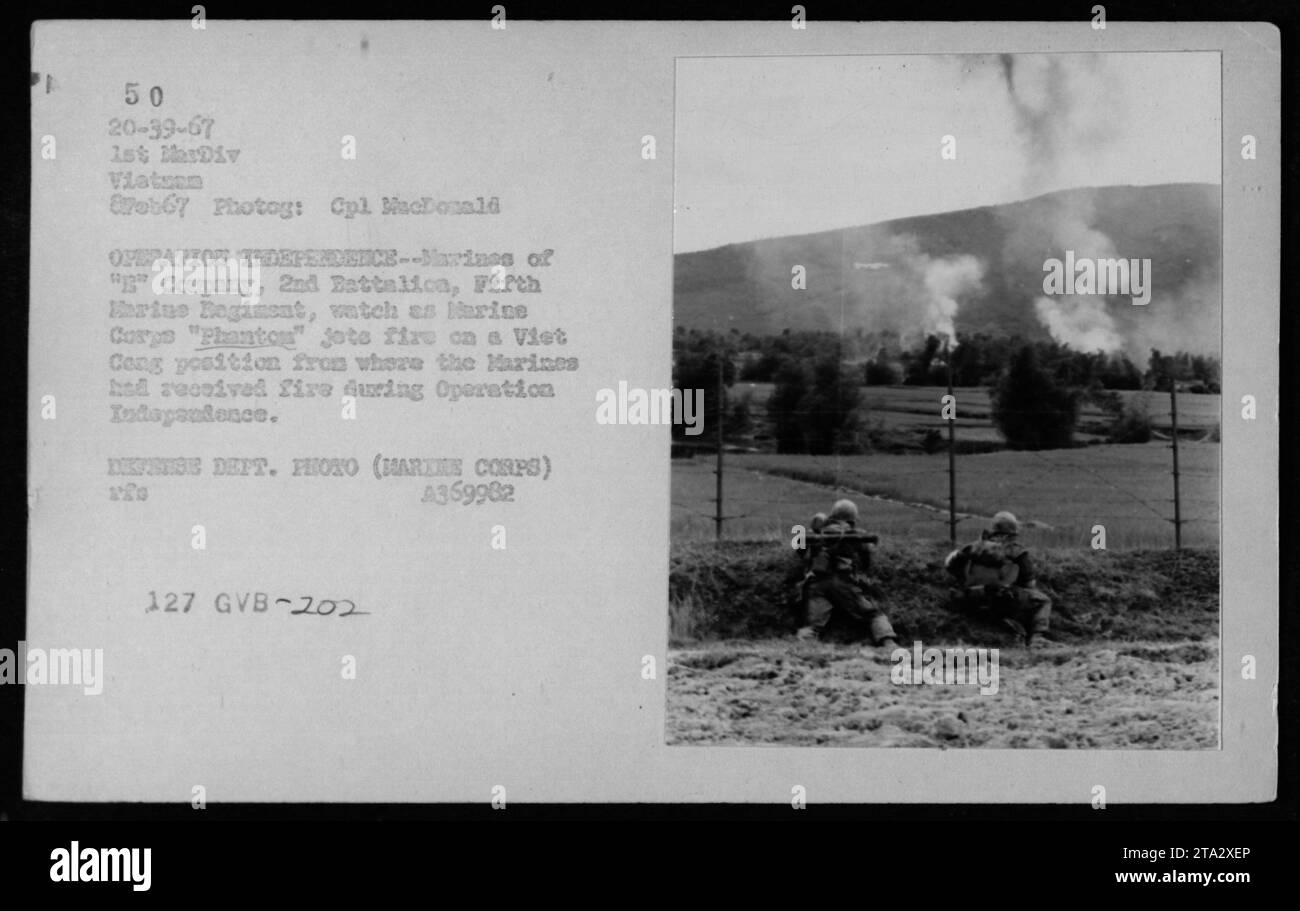 Marines of 'B' Company, 2nd Battalion, Fifth Marine Regiment, observe as a Marine Corps aircraft unleashes a barrage of artillery fire at a Viet Cong stronghold. This retaliatory action was taken after receiving enemy fire during Operation Independence. The photograph captures the intensity and danger of the Vietnam War. (Photograph taken on February 8, 1967, by Cpl. MacDonald) Stock Photo