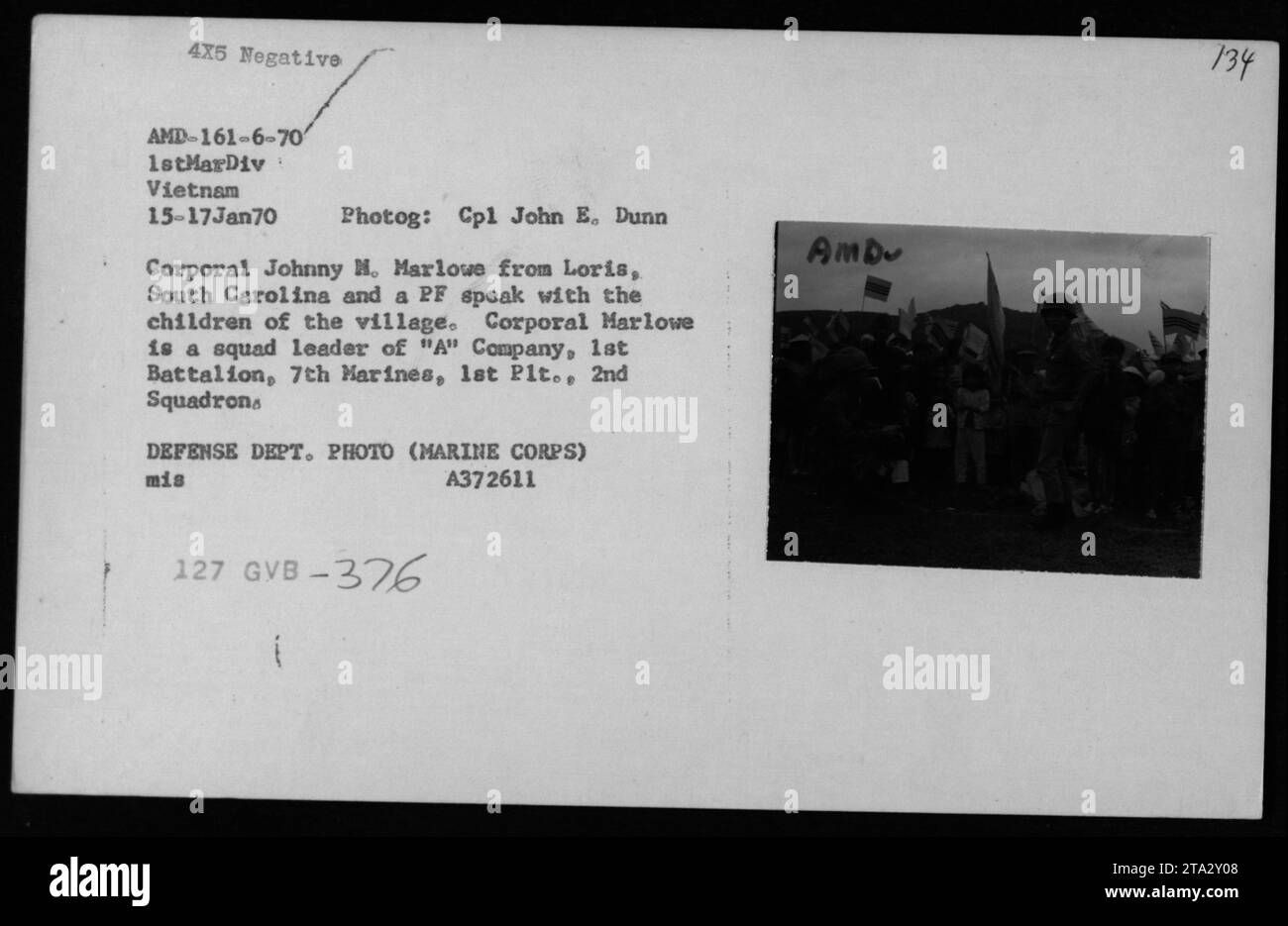'Cpl Johnny M. Marlowe from Loris, South Carolina and a PF interact with children in a Vietnamese village. Cpl Marlowe, a squad leader of 'A' Company, 1st Battalion, 7th Marines, is seen engaging in a friendly conversation during January 15-17, 1970 in Vietnam. This photograph captures moments of civilian interactions during the Vietnam War.' Stock Photo
