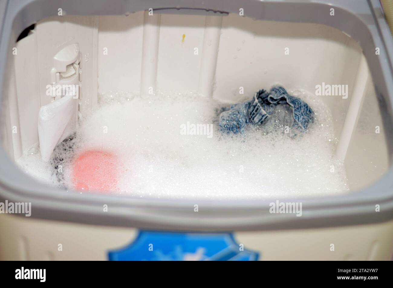 manual top load washing machine, laundry clothes washer, a home appliance used to wash laundry, user adds laundry detergent, which is sold in liquid, Stock Photo