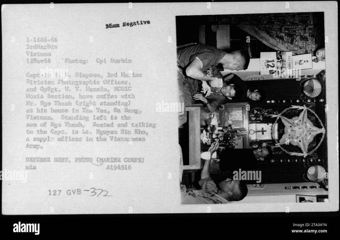 Captain B. E. Simpson, 3rd Marine Division Photography Officer, and Gysgt. W. T. Hannin, XCOIC Movie Section, having coffee with Mr. Ngo Thanh at his house in Ten Tos, a Bang, Vietnam. Lieutenant Nguyen Hiu Eho, a supply officer in the Vietnamese Army, also present. Photograph taken during the Vietnam War. Stock Photo