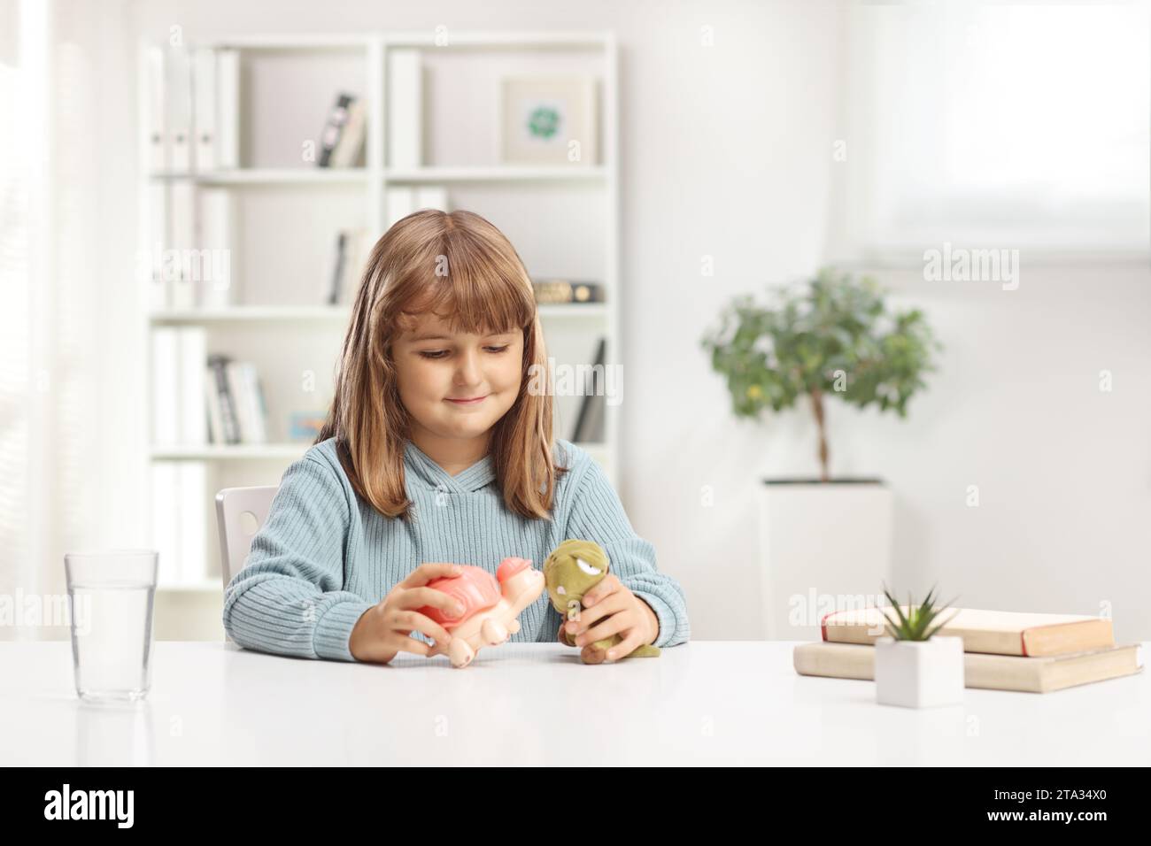 Cute little girl sitting at home and playing with animal toys Stock Photo
