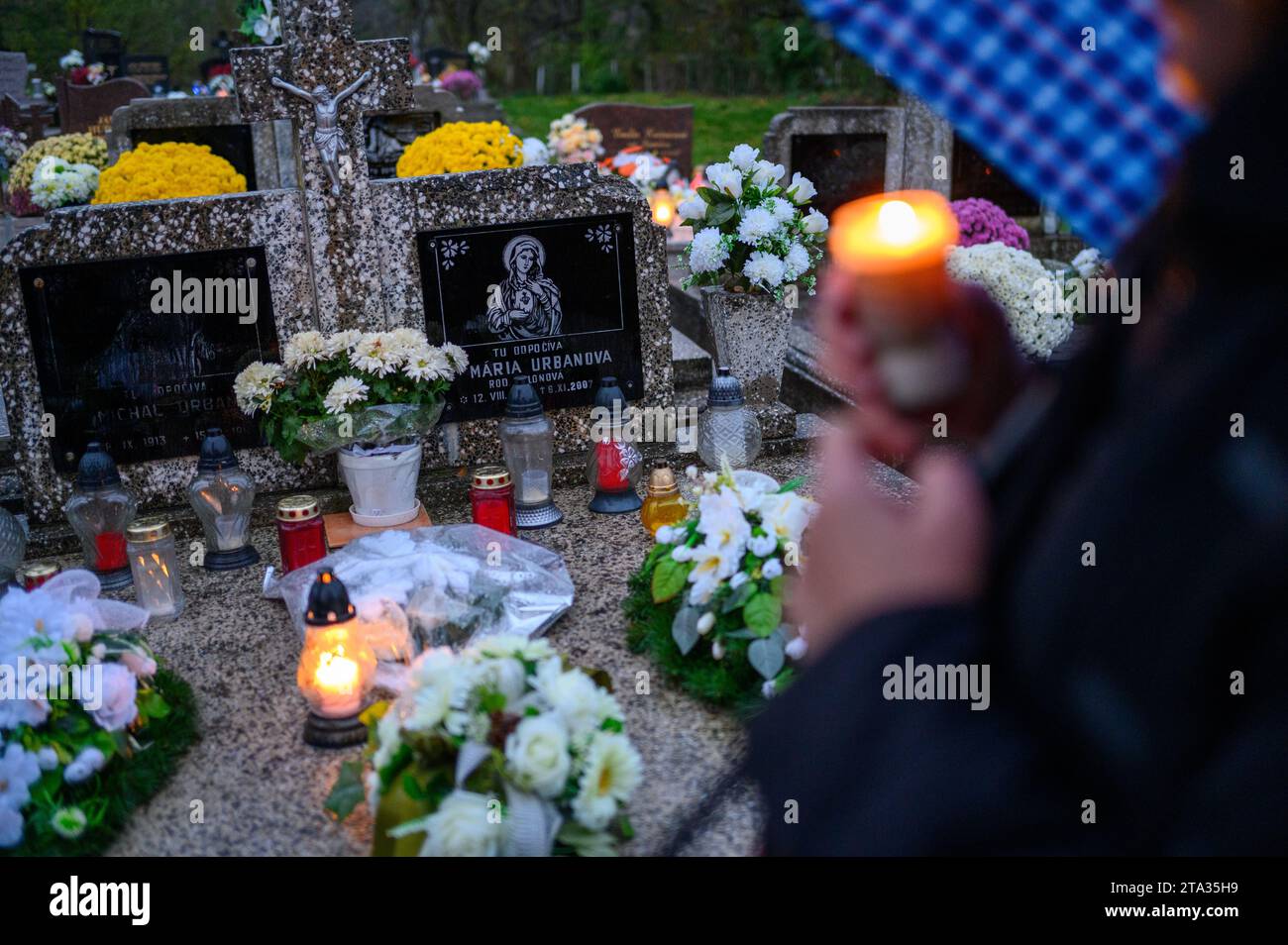 The faithful laying flowers and candles and praying for the departed on their grave. Stock Photo