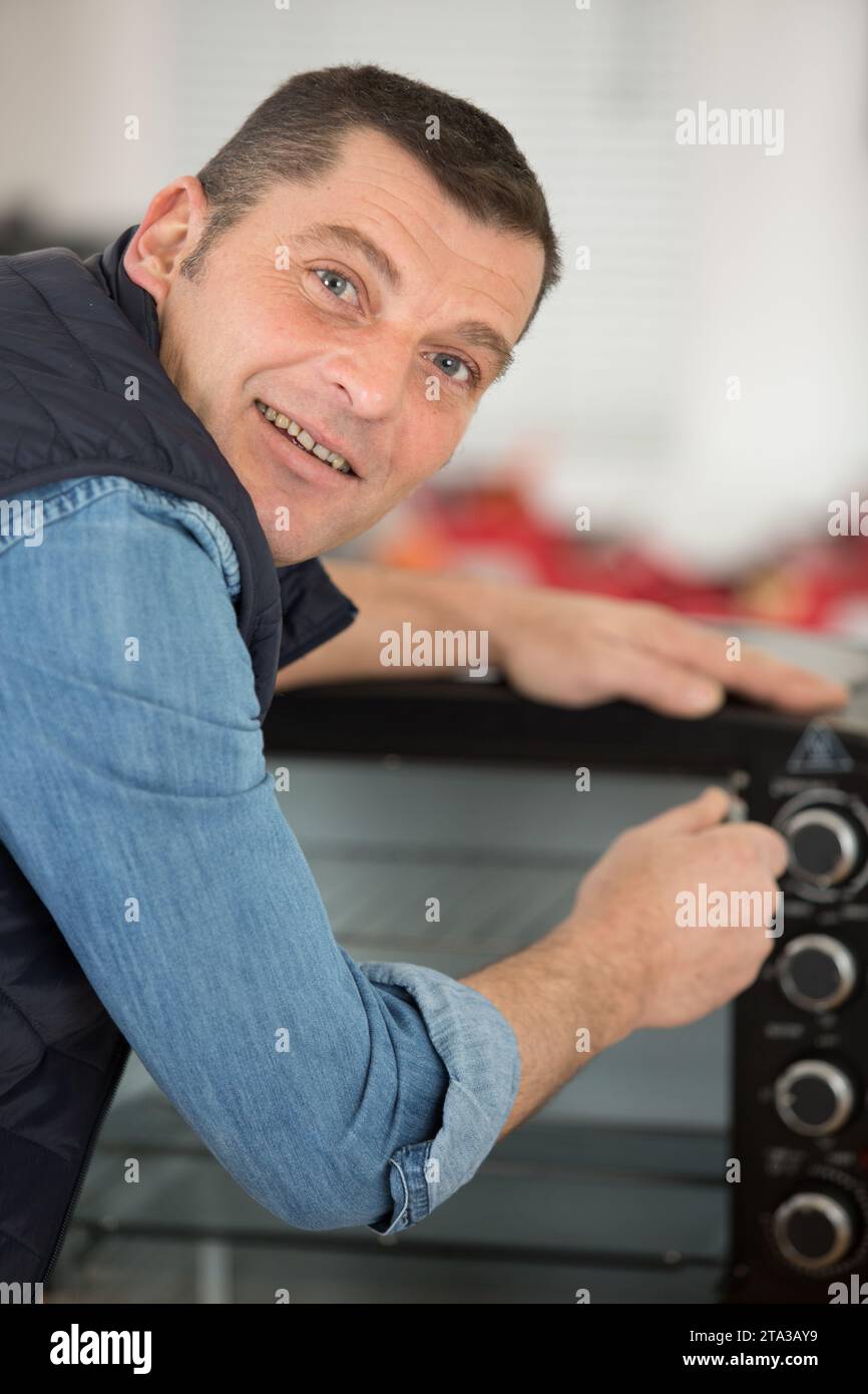 mature man repairing electric oven Stock Photo
