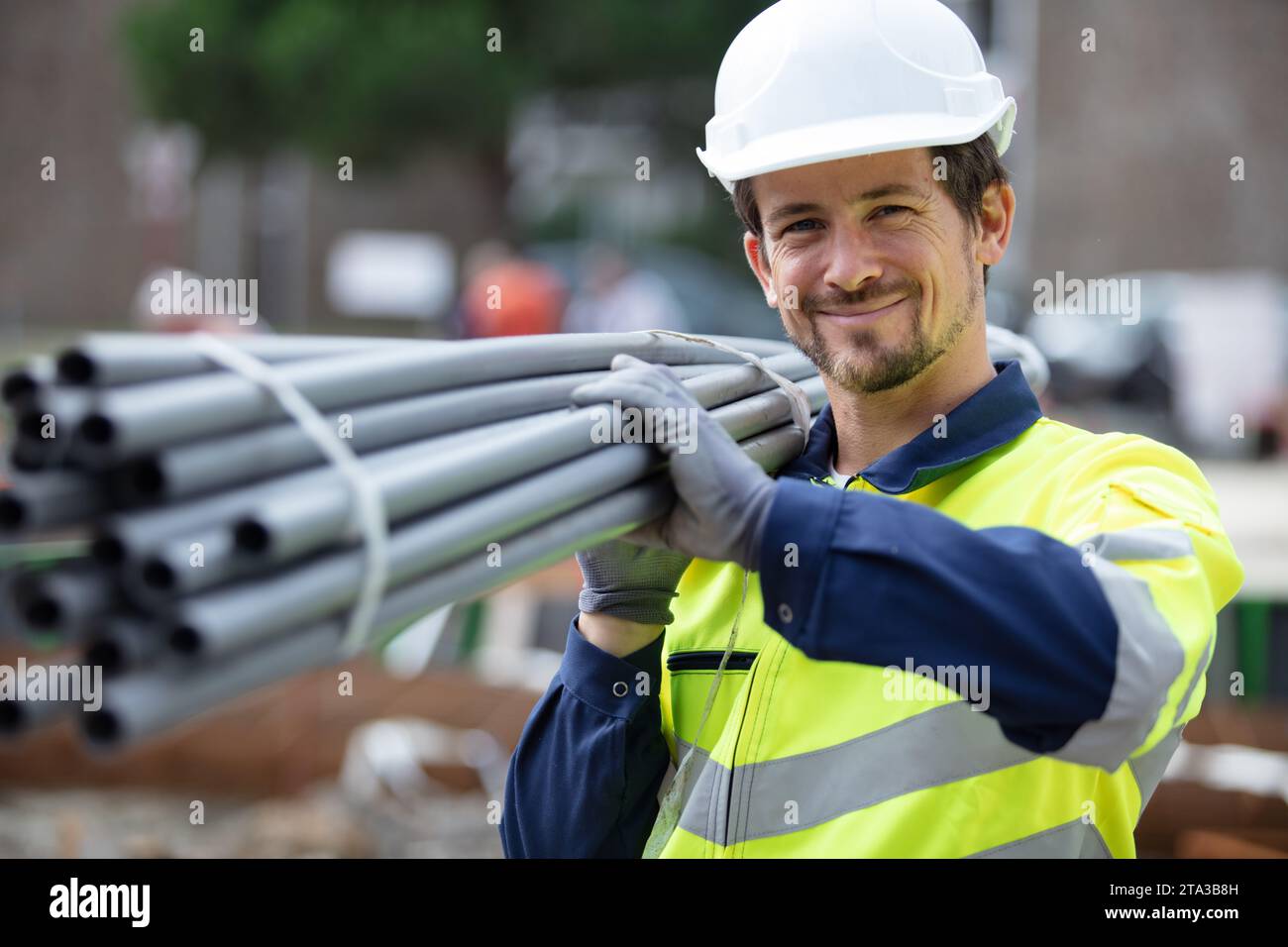 happy construction worker on site holding pipe Stock Photo - Alamy