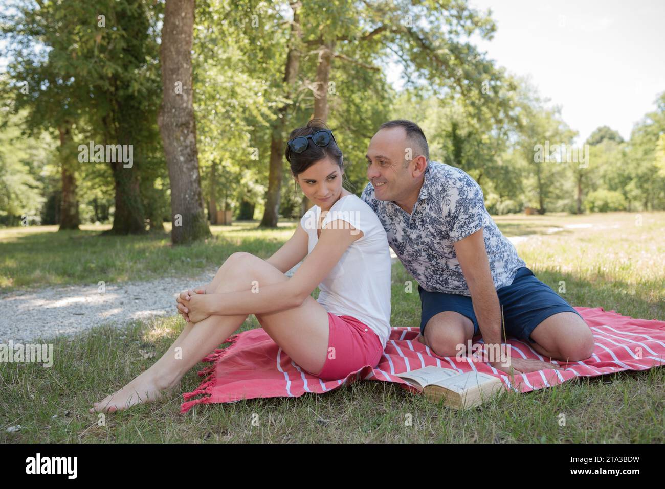 man tring to persuade sulking woman during picnic in park Stock Photo