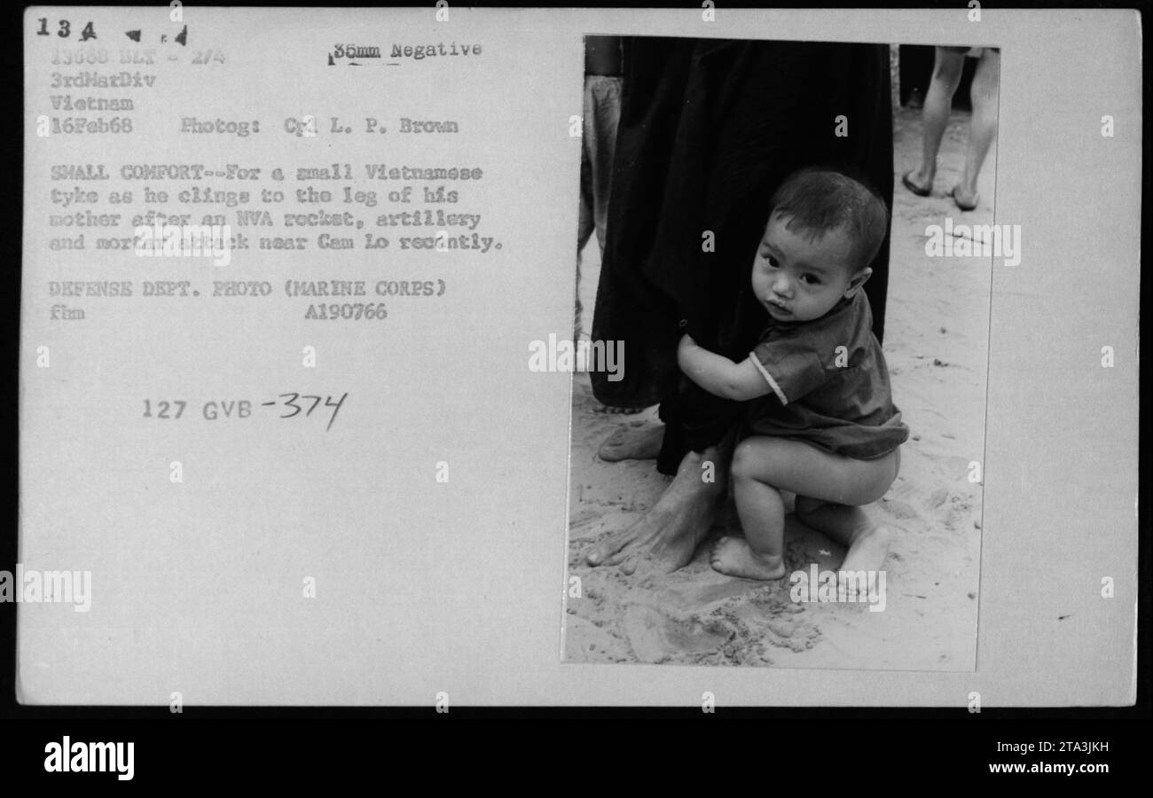 Vietnamese civilian clinging to his mother's leg after an NVA attack near Cam Lo in February 1968. The small child seeks comfort and safety amidst the devastation caused by rocket, artillery, and mortar projectiles. This photograph was taken by Cpl L.P. Brown of the 3rdHarDiv in Vietnam. Defense Department Photo (Marine Corps). A190766 127 GVB-374. Stock Photo