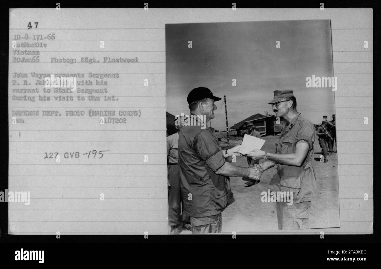 Actor John Wayne presents a warrant to Sergeant T. R. Jablonicky, promoting him to Staff Sergeant, during his visit to Chu Lai, Vietnam on June 20, 1966. The photograph was taken by SSgt. Flestwood as part of a series documenting American military activities during the Vietnam War. Stock Photo