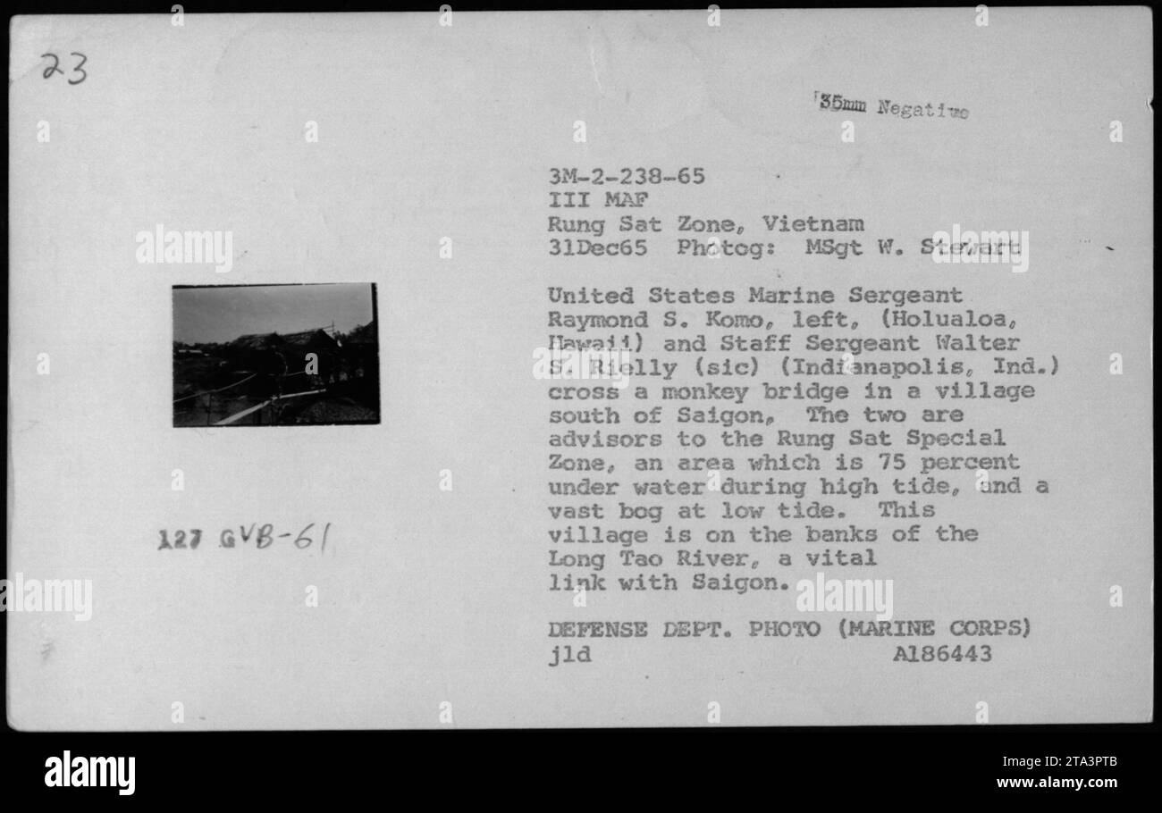 Marine Sergeant Raymond S. Komo and Staff Sergeant Walter S. Rielly cross a monkey bridge in a village south of Saigon. They work as advisors in the Rung Sat Special Zone, a region heavily affected by tides and situated on the Long Tao River, an important connection to Saigon. The photo was taken on December 31, 1965, by MSgt W. Stewart. Stock Photo