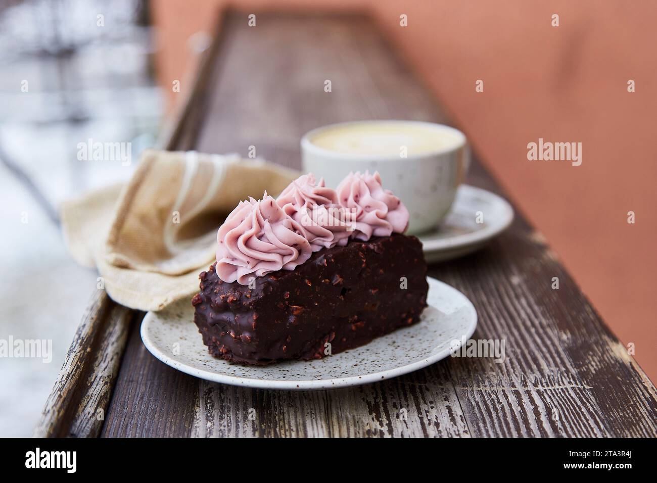 Vegan brownie cake with cup of cappuccino outdoor. Coffee with dessert. Winter aesthetics. Stock Photo