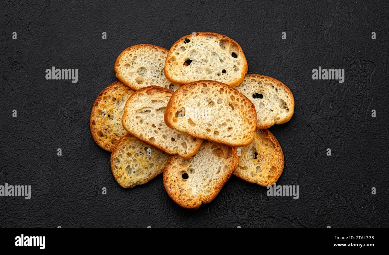 Bruschetta crackers, bread croutons on black background, top view Stock Photo