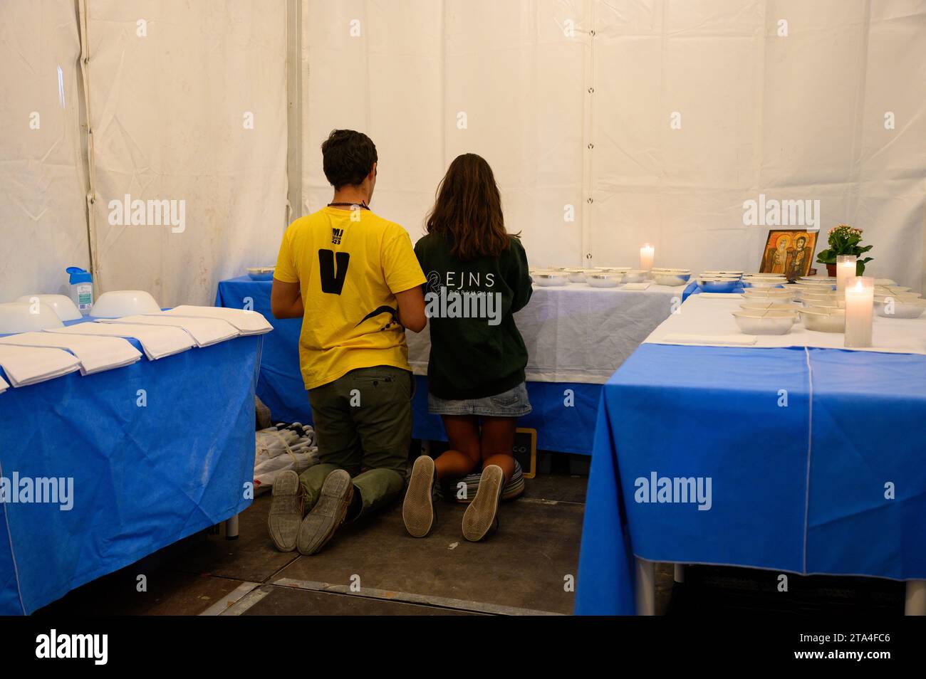 A boy and a girl praying in adoration in front of the Eucharist to be distributed on the next day at Holy Mass. Vigil with young people in Parque Tejo. Stock Photo