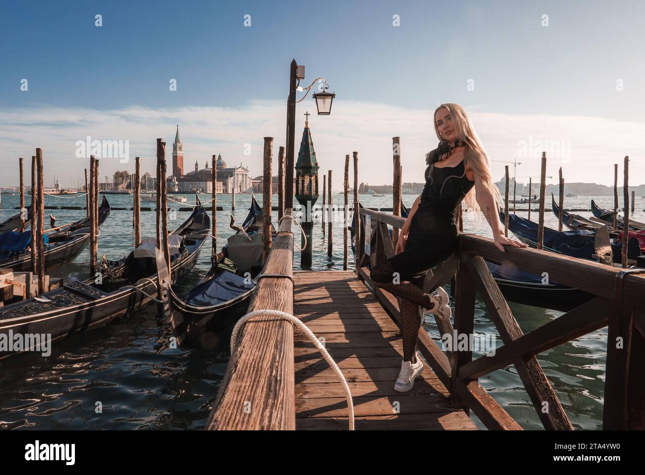 Elegant Woman in Black Dress Posing on Venice Pier with Gondolas on a