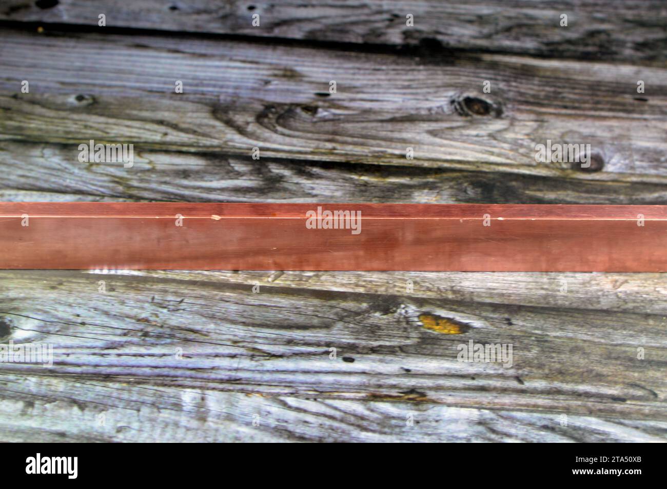 Long heavy copper bar, Copper is a mineral, an element and a metal, used in wiring, roofing, pipes, pots and pans, decorations and artworks, jewelry a Stock Photo
