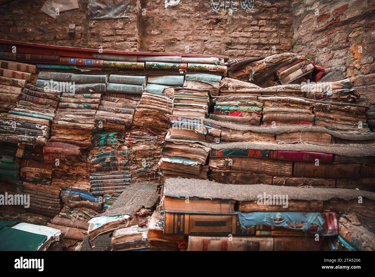 Vintage books in disarray in dimly lit, cozy room with warm sunlight streaming through window Stock Photo