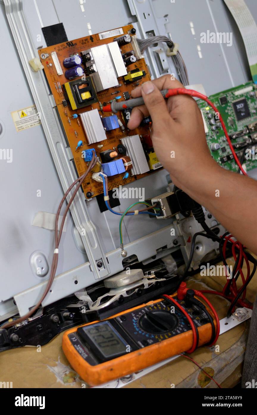 Cairo, Egypt, October 3 2023: A technician Engineer using a digital multimeter, LCD TV Television main board power circuit, wires, transformers, resis Stock Photo