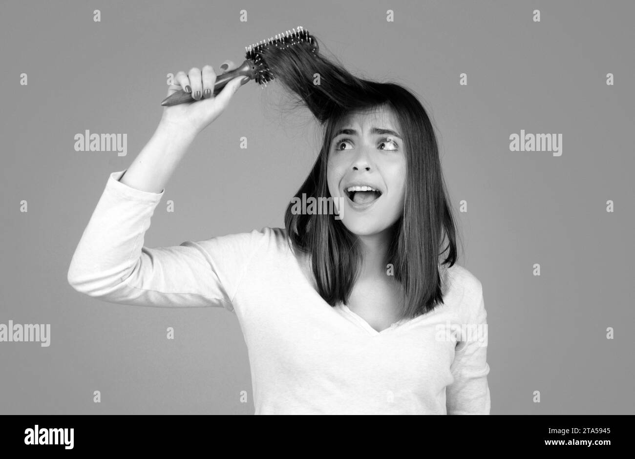 Excited funny woman combing hair. Portrait of female model with a comb