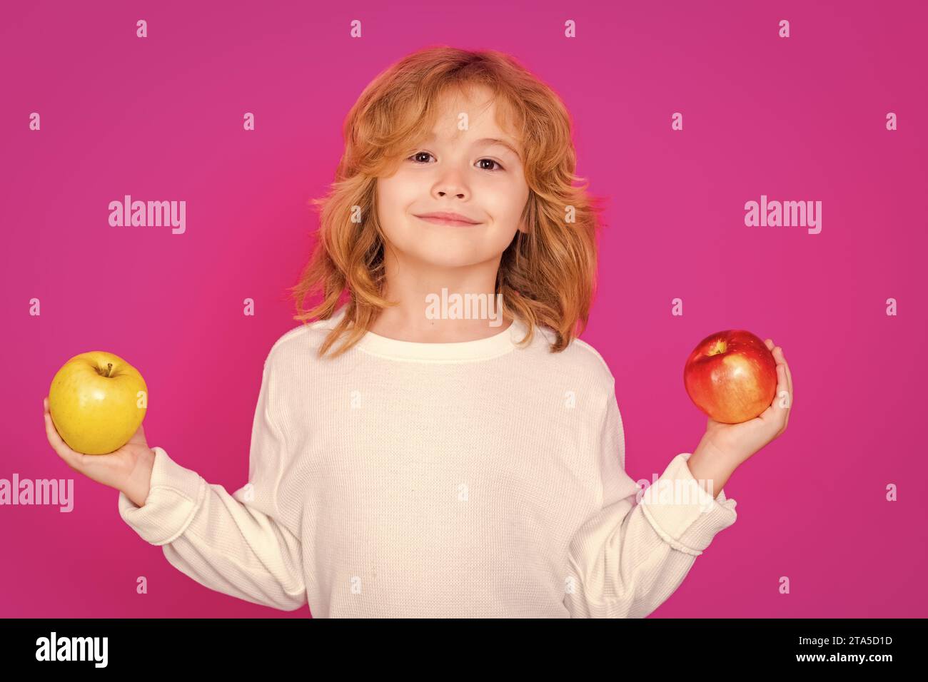 Kid with apple in studio. Studio portrait of cute child hold apple isolated on pink background Stock Photo