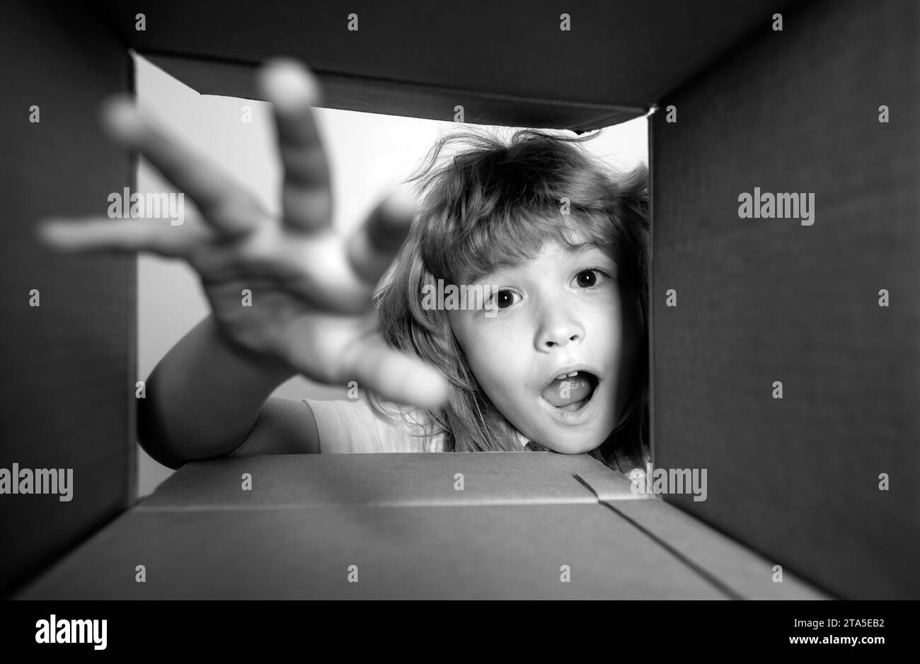 Child looking inside cardboard box, bottom view. Delivering your purchase. Kids celebrate birthday. Birthday gift. Shocked kids, amazed kids emotions Stock Photo