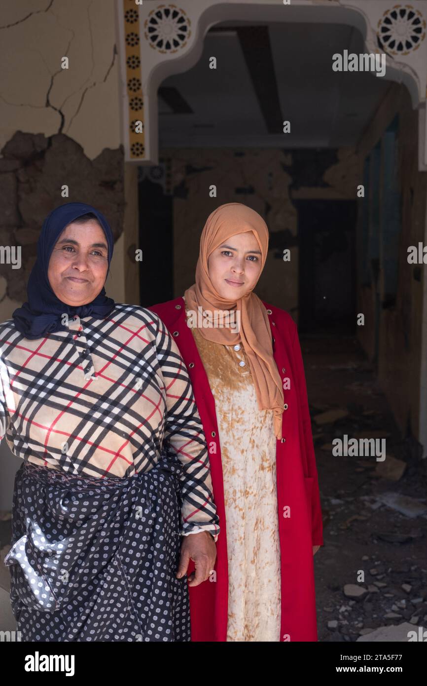 Mother and daughter stand in the doorway of an earthquake-damaged house in Ambdour, Atlas Mountains, Morocco Stock Photo