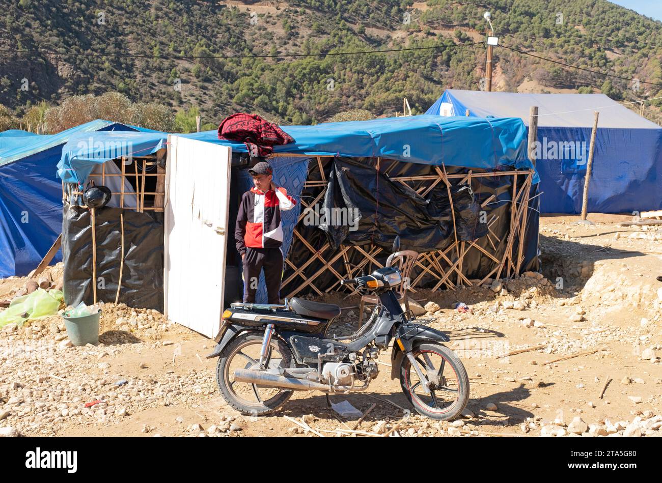 Teenage boy standing outside an emergency shelter in Sidi Hssain, Atlas Mountains, Morocco Stock Photo