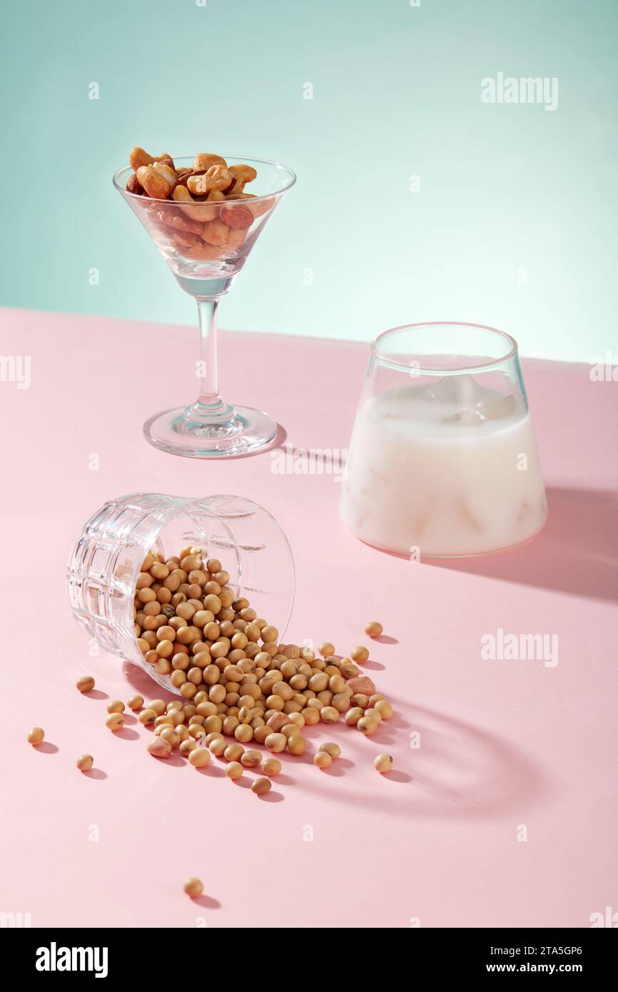 Cocktail glass contained some types nuts displayed with a cup of milk and a lot of soybeans. Soy milk supports a healthy heart from multiple angles Stock Photo