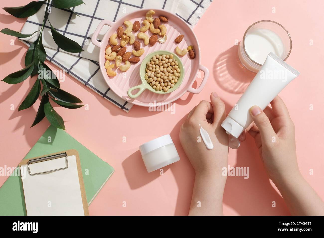 Hand model with a smear on and holding a white tube. Pink dish