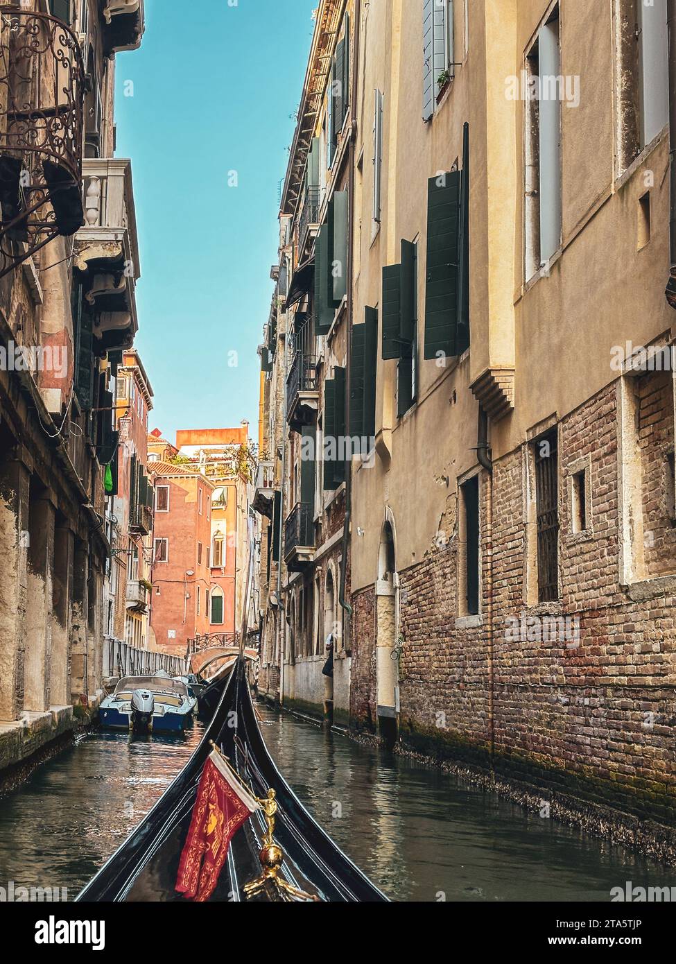Gondola moving between houses in narrow canals within the city of Venice, Italy Stock Photo