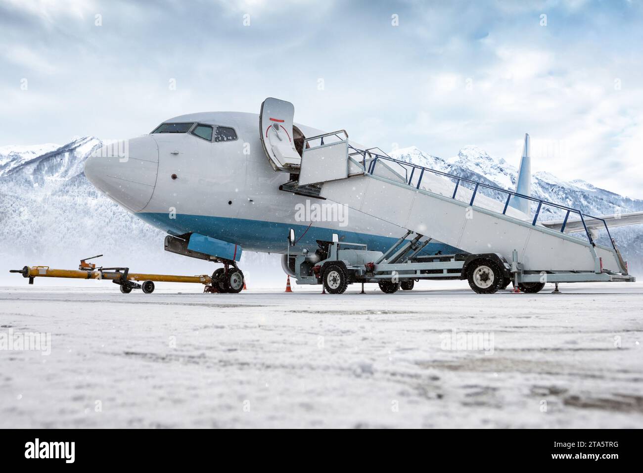 Passenger airliner with air-stairs on the airport apron in a blizzard ...