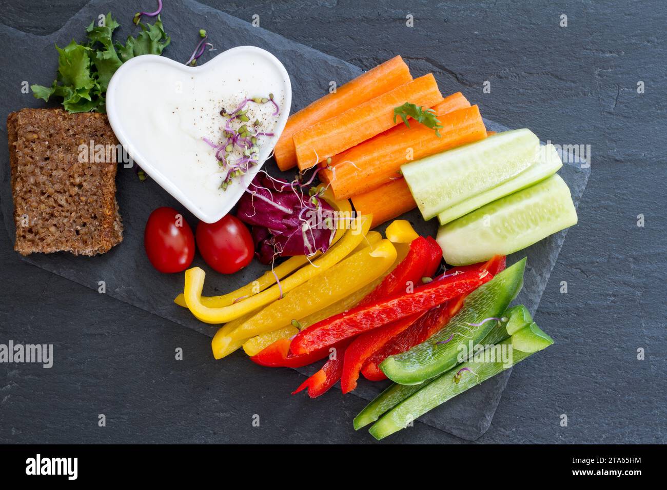 Assorted fresh chopped vegetables with dip on dark background, tasty and healthy snack Stock Photo