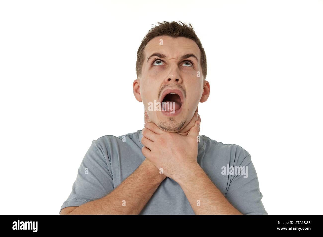 guy grimaces and grabs his throat with his hands on white background Stock Photo Alamy