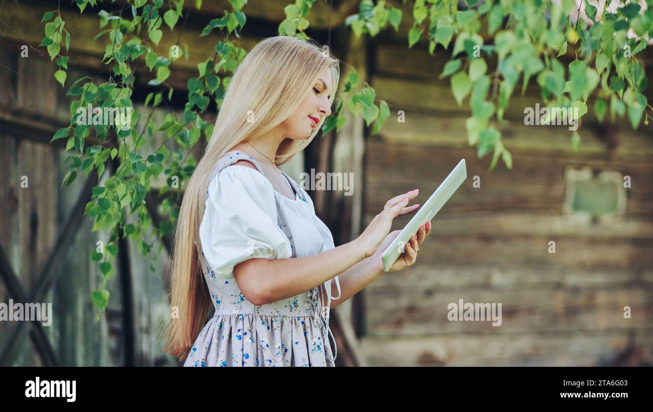 Village Slavic girl flipping a tablet in the countryside. Stock Photo