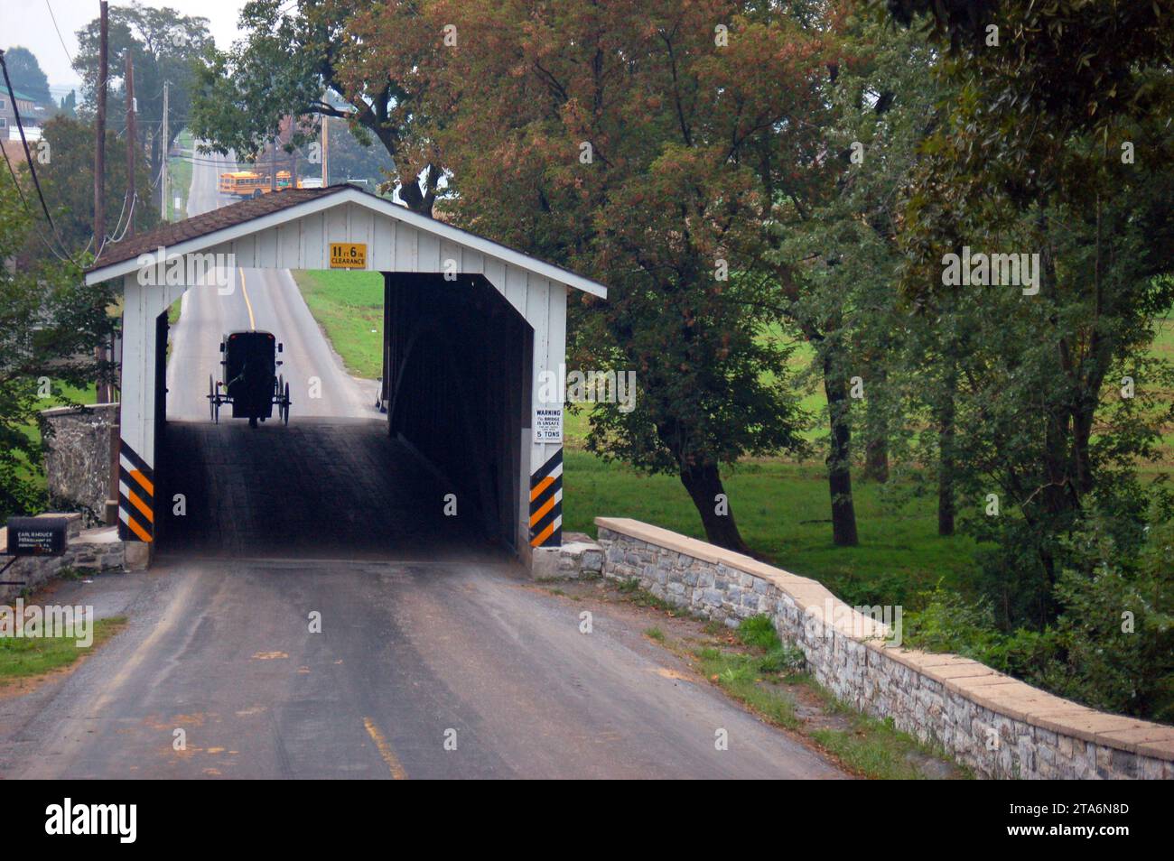 An Amish horse and buggy prepares to cross a historic covered bridge in the Pennsylvania Dutch country of Lancaster County Stock Photo
