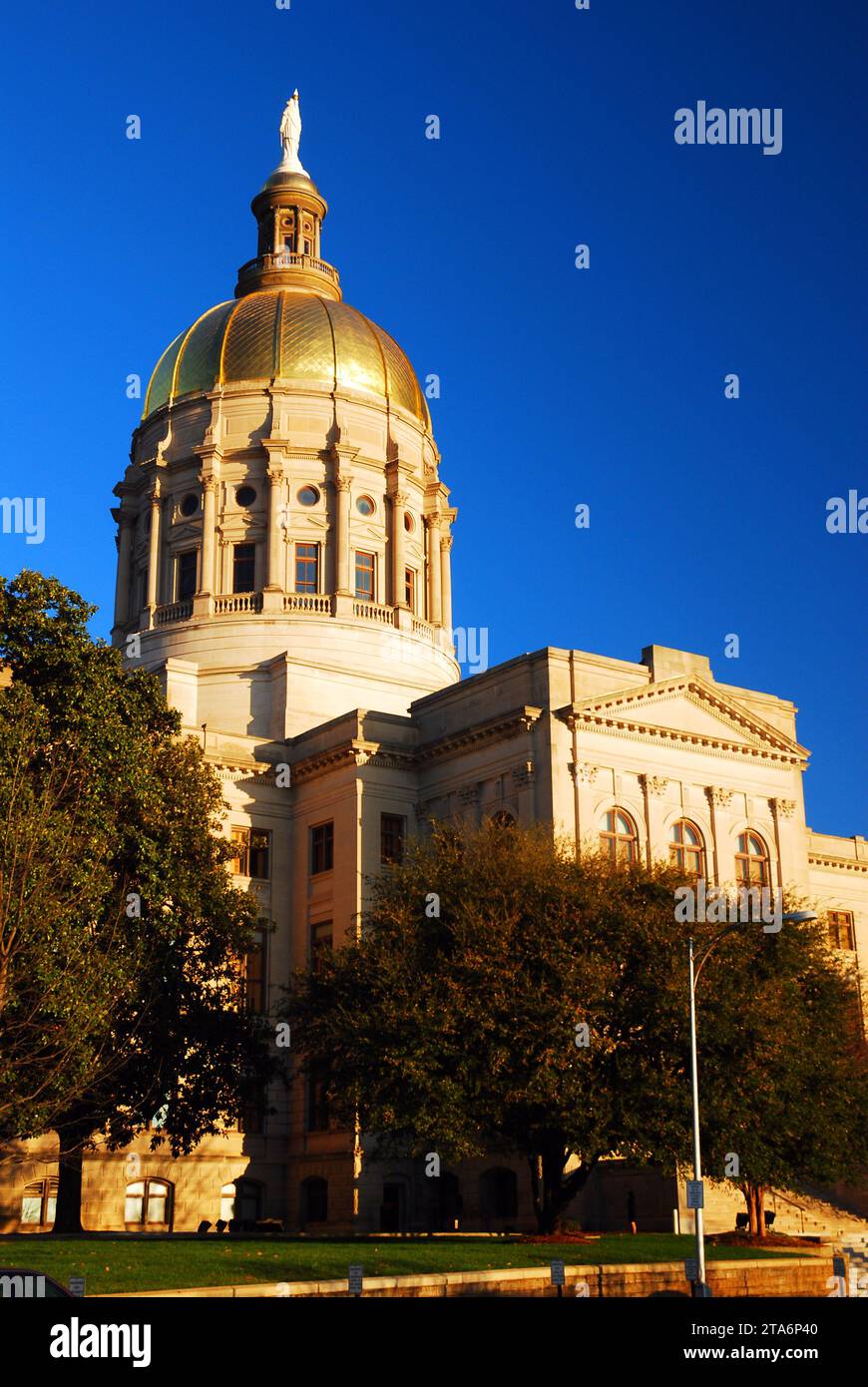 The gold dome of the Georgia State Capitol, home to the politics and political life of the state government, rises over the tree line Stock Photo