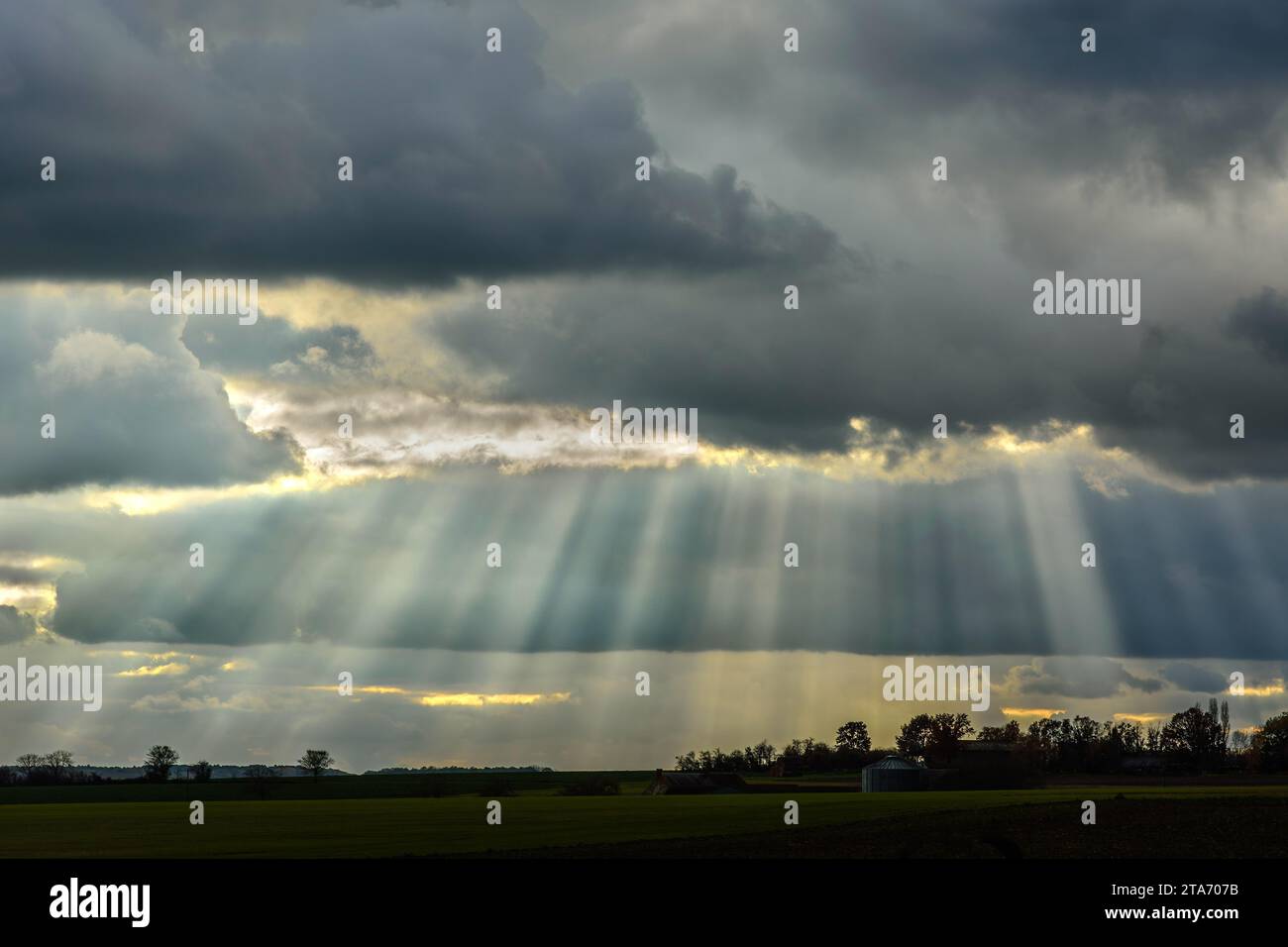 Sun-rays shining through storm-clouds on late winter afternoon - central France. Stock Photo