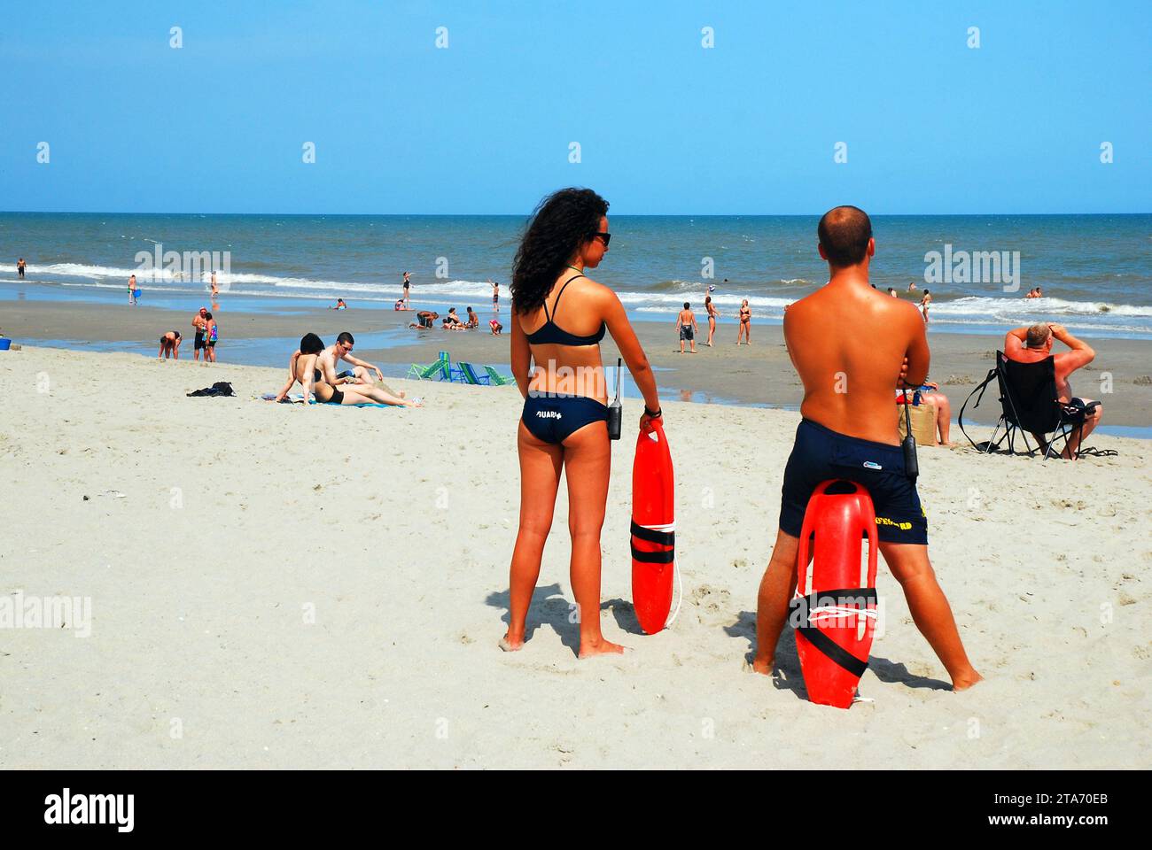 Two young adult lifeguards watch over the action of the waves in the ocean at Myrtle Beach South