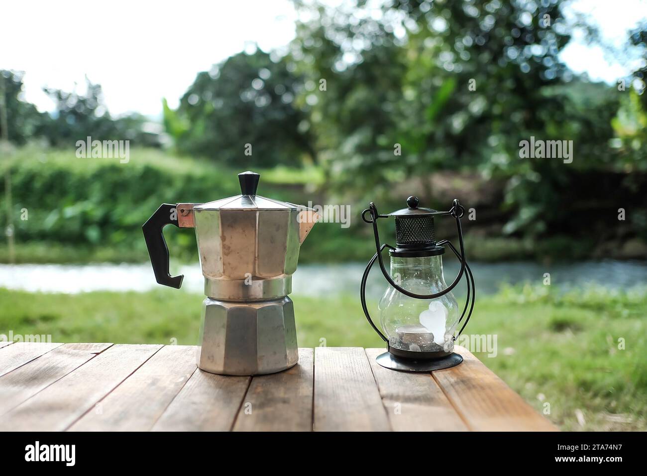 https://c8.alamy.com/comp/2TA74N7/vintage-electric-lantern-and-glass-dripper-carafe-on-a-folding-table-for-camping-at-river-side-blur-background-2TA74N7.jpg