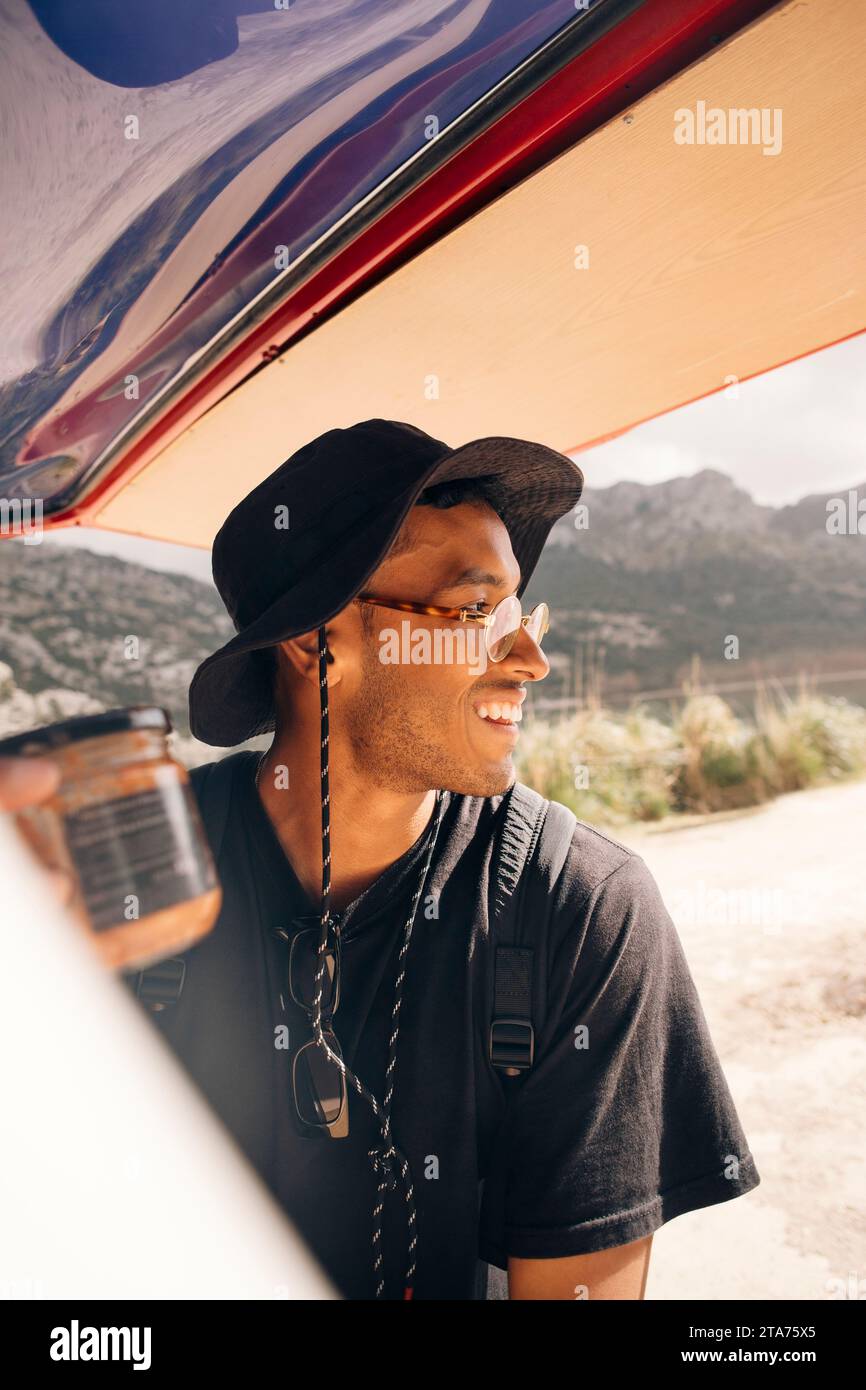 Smiling young man looking away while standing near van Stock Photo