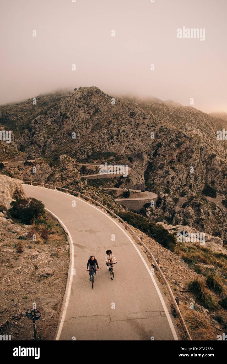 High angle view of male and female friends cycling on road against mountains Stock Photo