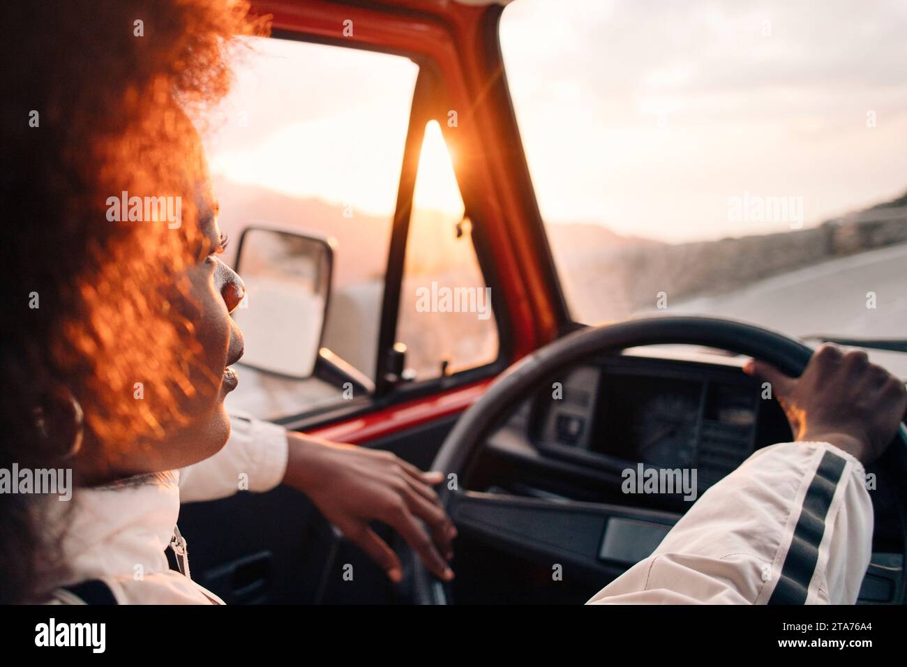 Young man driving van at sunset on vacation Stock Photo