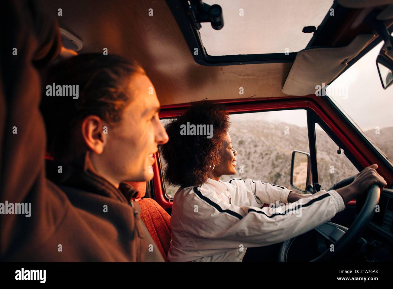 Smiling woman enjoying road trip with male friend sitting in van Stock Photo