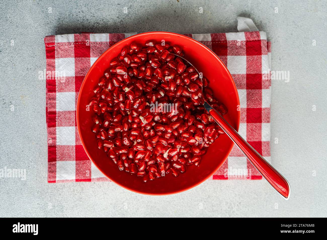 Overhead view of a bowl of Ripe pomegranate seeds on a red folded checked napkin Stock Photo