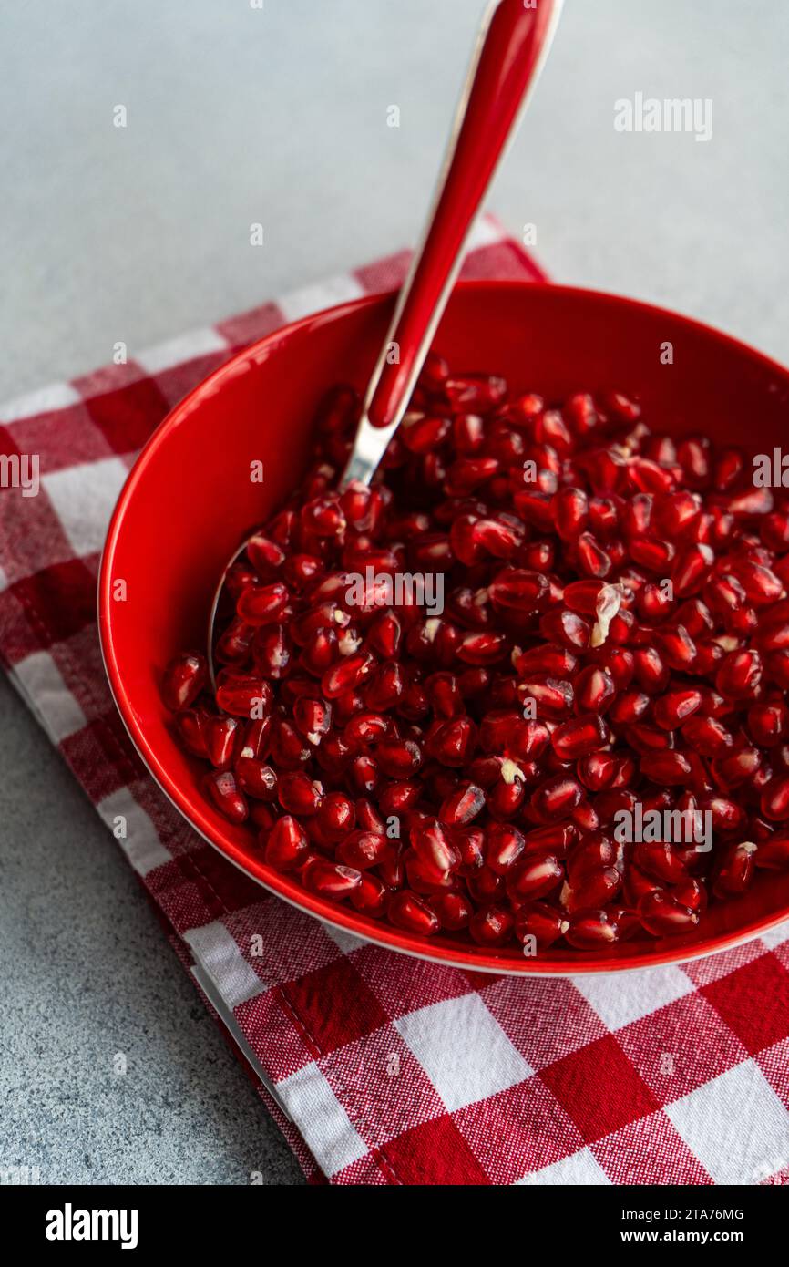 Close-up of a bowl of Ripe pomegranate seeds on a red folded checked napkin Stock Photo