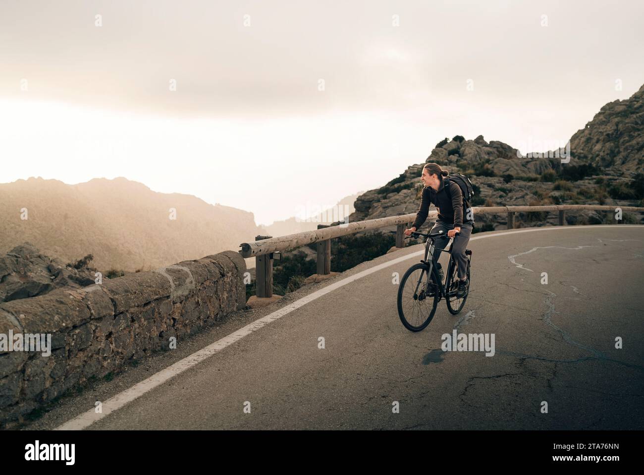 Young man looking at mountains while cycling on road Stock Photo